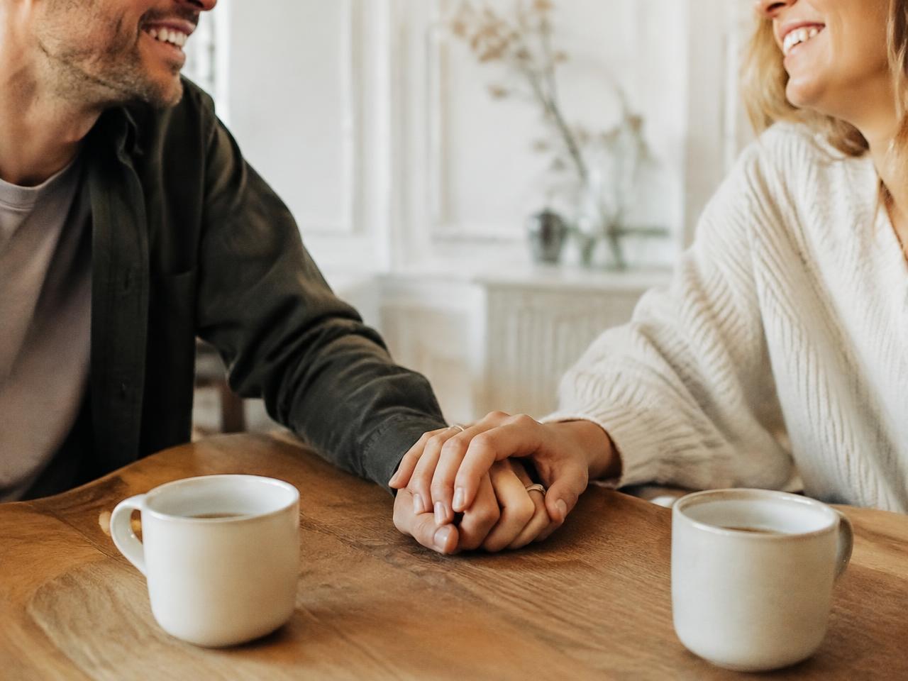A couple holding hands over morning coffee